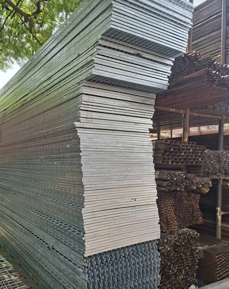 Stacked steel grating and sheet with coiled pipe in the background.