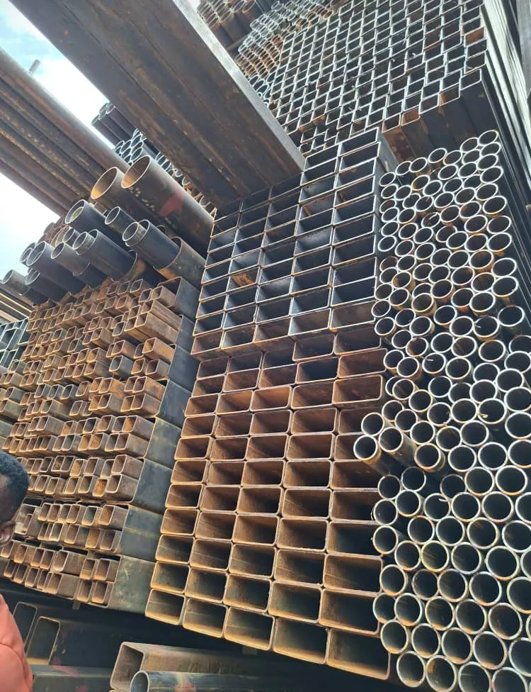 Yard worker beside stacks of square tube and round pipe stock.
